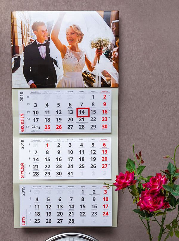 Kalendarz Trójdzielny ze zdjęciami wiszący na ścianie